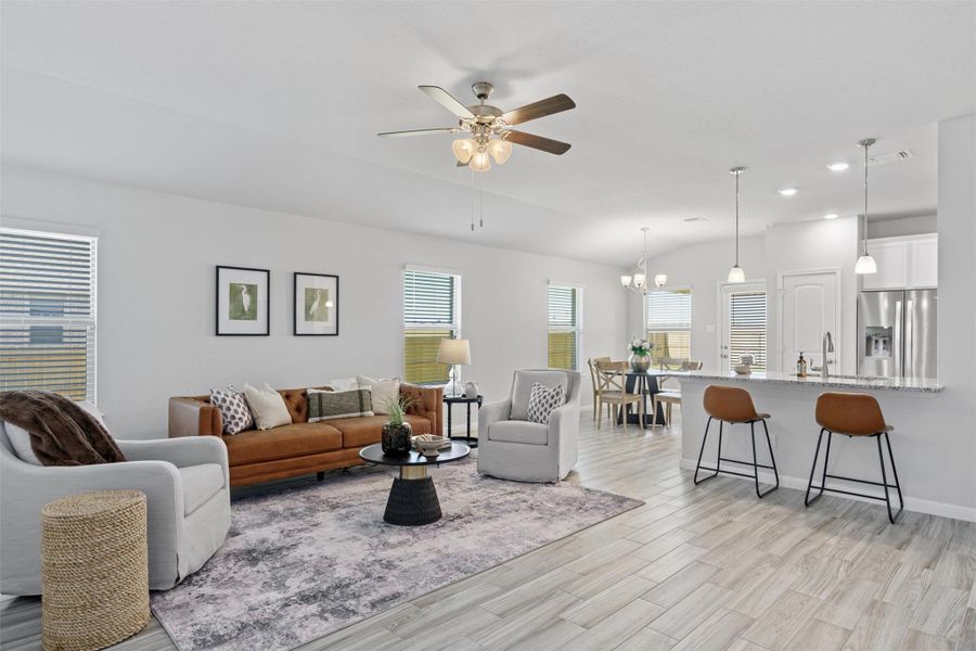 Living room with a ceiling fan, light wood finished floors, lofted ceiling, a chandelier, and recessed lighting