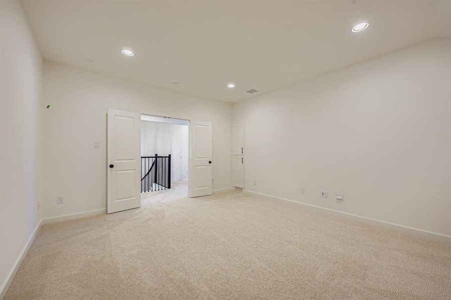Empty room with light carpet and recessed lighting