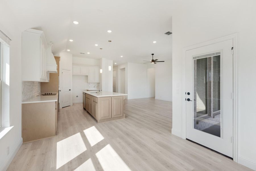 Open kitchen and living area with white cabinets, center island, and light wood floors