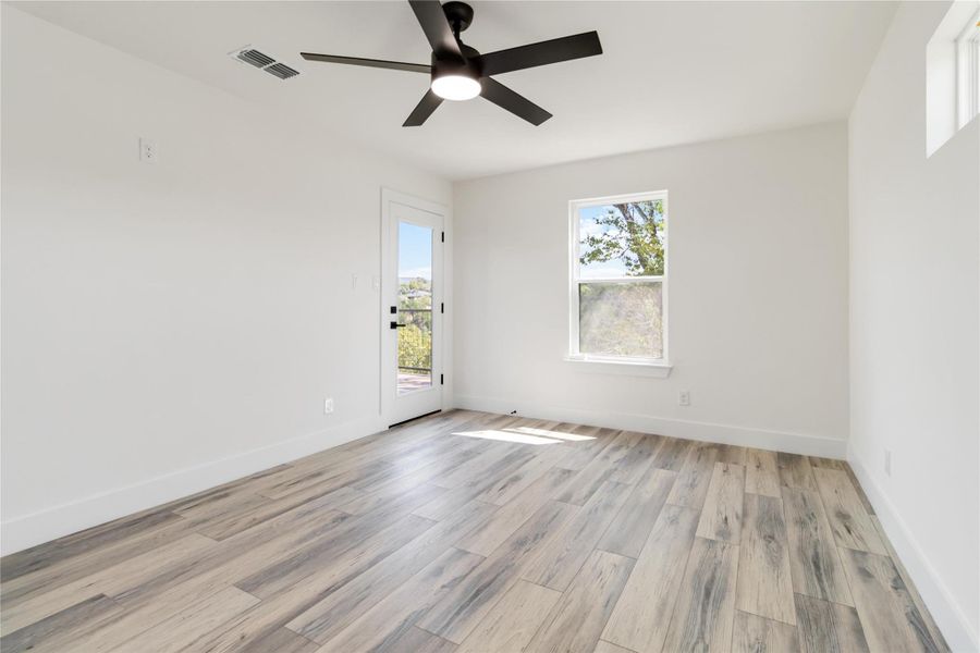 Second-level primary bedroom featuring a large window, ceiling fan, and serene views of beautiful oak trees. Second-level primary bedroom featuring a large window, ceiling fan, and serene views of beautiful oak trees.