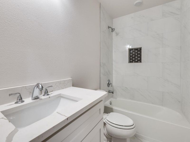 Full bathroom with vanity, tiled shower / bath combo, and toilet