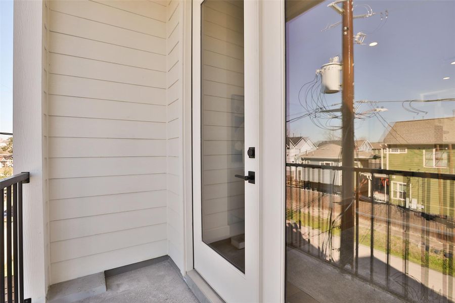 This charming private balcony offers a peaceful retreat just off the interior living space. The sleek black metal railing provides an open feel, and the glass-paneled door allows natural light to flow inside.