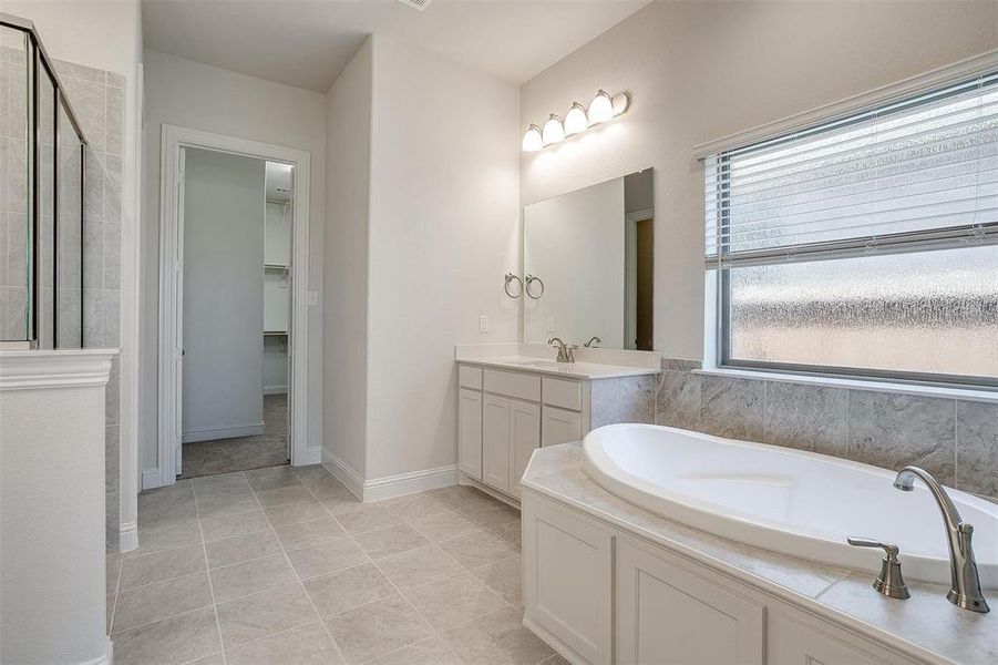 Bathroom featuring tile patterned floors, a tub to relax in, and vanity