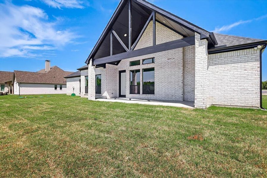 Rear view of house with brick siding and a lawn