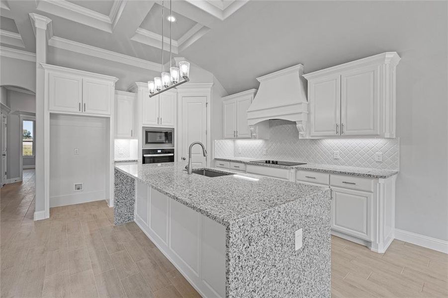 Kitchen featuring light stone countertops, sink, stainless steel appliances, white cabinets, and premium range hood