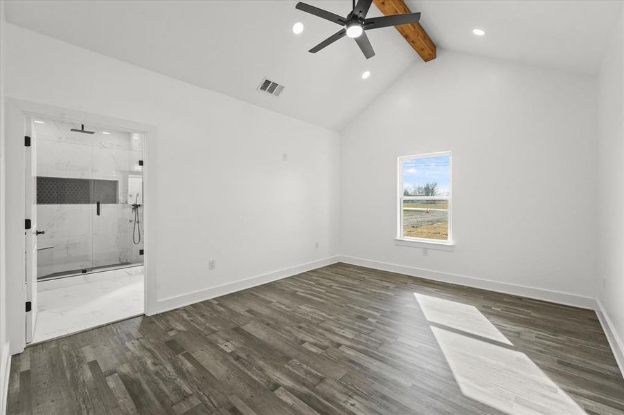 Unfurnished bedroom with connected bathroom, high vaulted ceiling, dark hardwood / wood-style floors, beamed ceiling, and ceiling fan