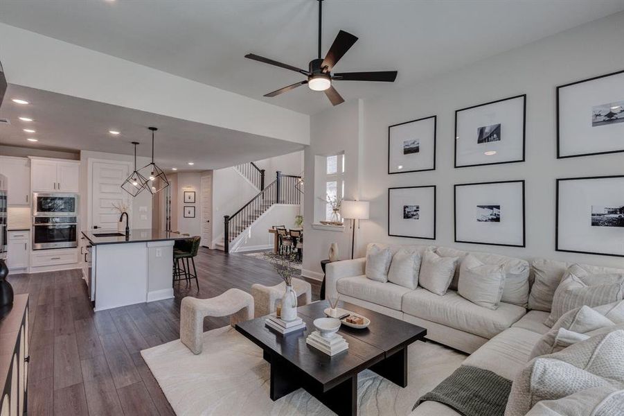 Living area with stairs, recessed lighting, dark wood-style flooring, a ceiling fan, and a chandelier
