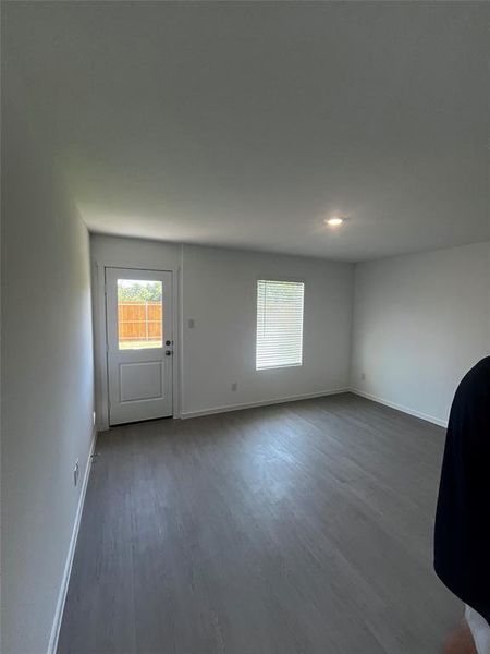 Spacious room featuring wood-finish flooring, recessed lighting, and a rear door with integrated window Spacious room featuring wood-finish flooring, recessed lighting, and a rear door with integrated window