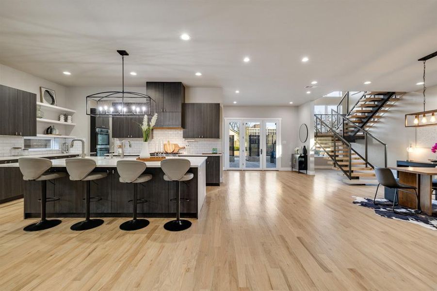 Kitchen with a kitchen bar, a kitchen island with sink, hanging light fixtures, and dark brown cabinetry