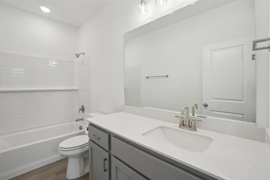 Full bathroom with hardwood / wood-style floors, vanity, toilet, and shower / tub combination