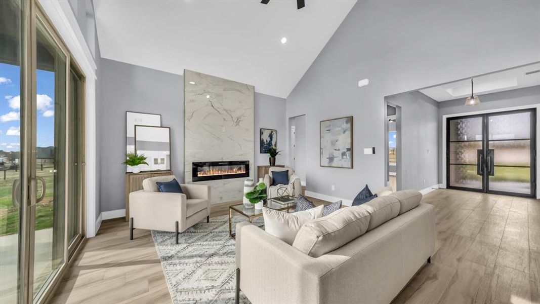 Living room featuring a high end fireplace, high vaulted ceiling, light wood-type flooring, and recessed lighting