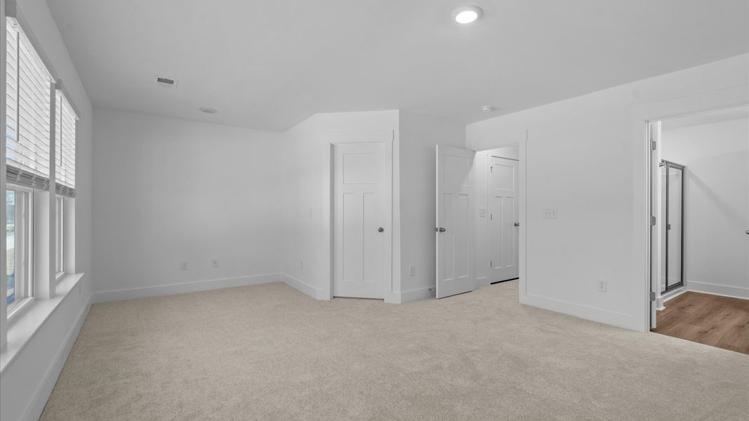 Superior design meets vibrant comfort in this primary suite with carpeted floors and walk-in closet at Gresham Station