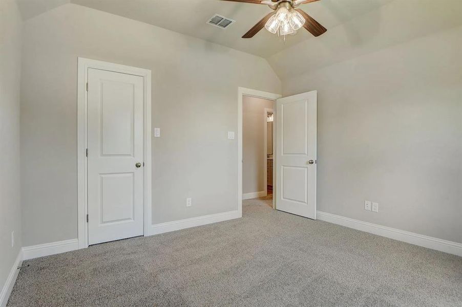 Unfurnished bedroom featuring vaulted ceiling, carpet flooring, baseboards, and a ceiling fan