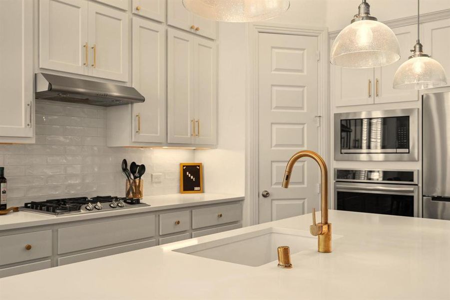 The kitchen features gorgeous champagne gold fixtures & hardware.