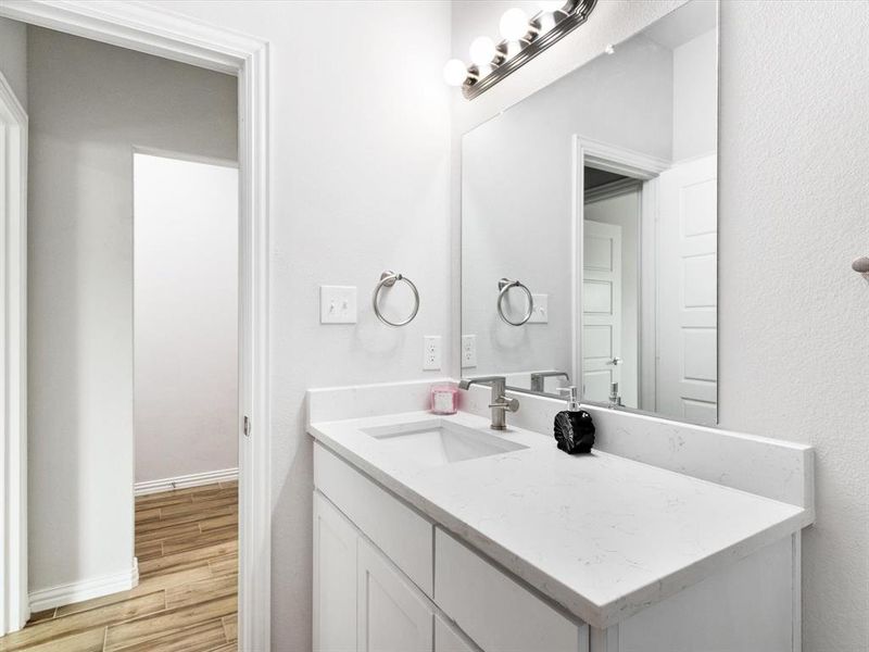 Bathroom featuring a single vanity with white cabinetry, a light-colored countertop, and an integrated sink with a brushed nickel faucet