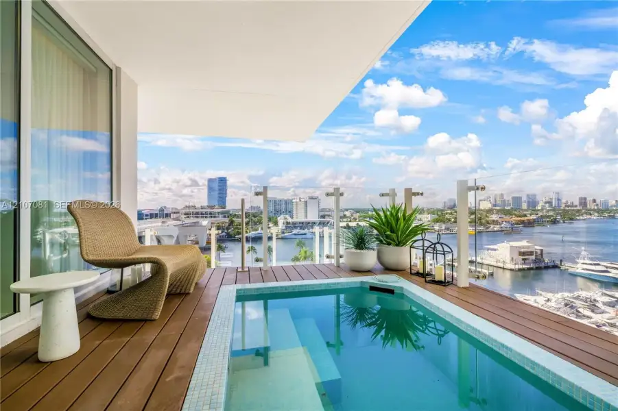 Covered balcony featuring an inset plunge pool, wood-finish decking, and a glass-paneled railing Covered balcony featuring an inset plunge pool, wood-finish decking, and a glass-paneled railing