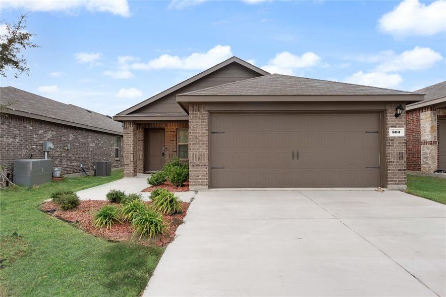 Ranch-style house featuring brick siding, driveway, a garage, and a front lawn