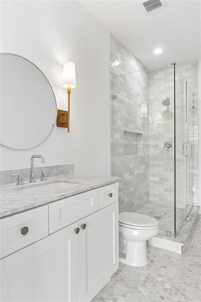 Bathroom with vanity, toilet, and a shower with shower door