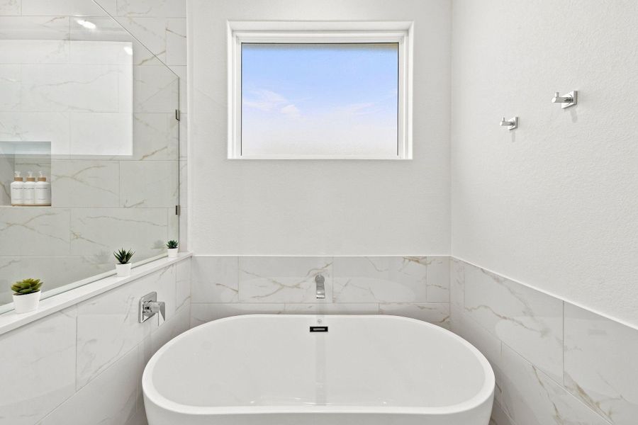 Spa-inspired primary bathroom featuring a relaxing soaking tub, separate shower, and abundant natural light. Spa-inspired primary bathroom featuring a relaxing soaking tub, separate shower, and abundant natural light.