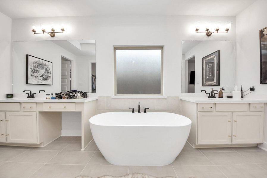 Spa-inspired primary bath with freestanding tub, large mirrors, and abundant counter space.