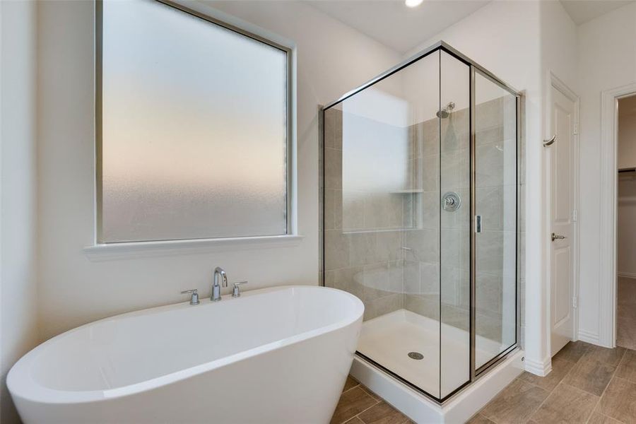 Bathroom featuring wood-type flooring and shower with separate bathtub