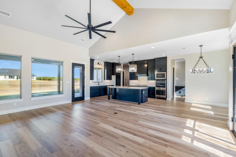 Kitchen featuring a center island, a kitchen breakfast bar, hanging light fixtures, appliances with stainless steel finishes, and beam ceiling