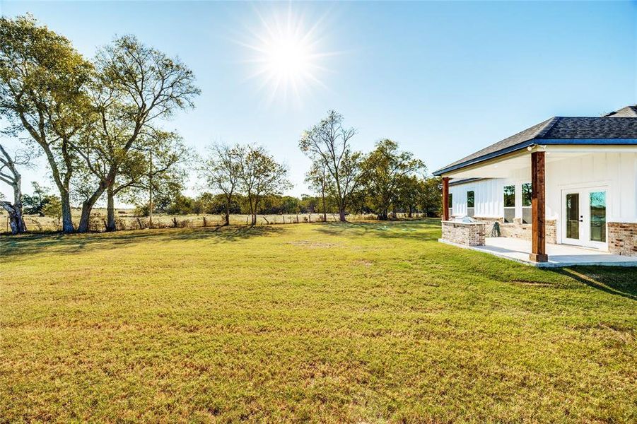 View of grassy yard featuring french doors and a patio