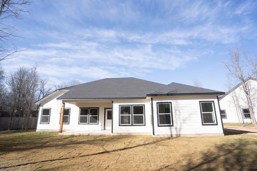 Back of house with a patio area, a yard, and a shingled roof