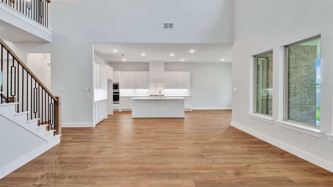 Unfurnished living room with a high ceiling, light wood-type flooring, and sink