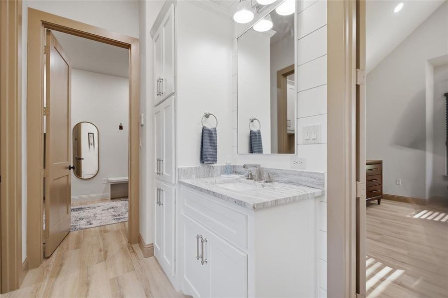 Vanity area featuring a light-toned countertop, white cabinetry with silver hardware, and a framed mirror with overhead lighting