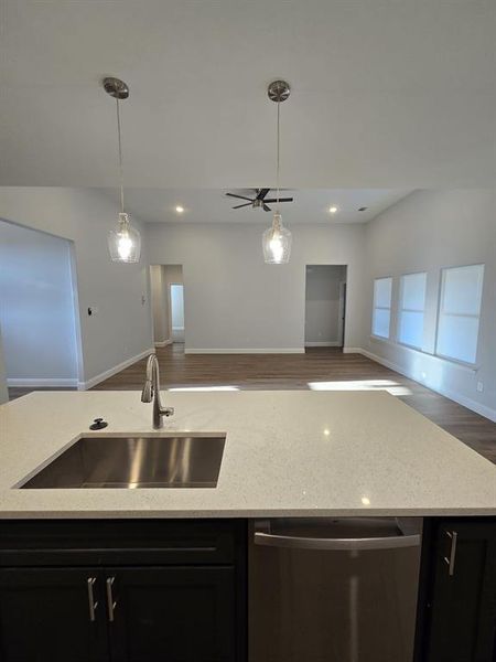 Kitchen featuring sink, dishwasher, wood-type flooring, and light stone countertops