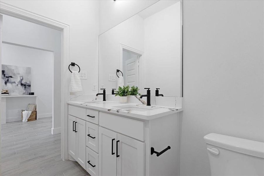 Bathroom featuring double vanity, toilet, a sink, and wood finished floors