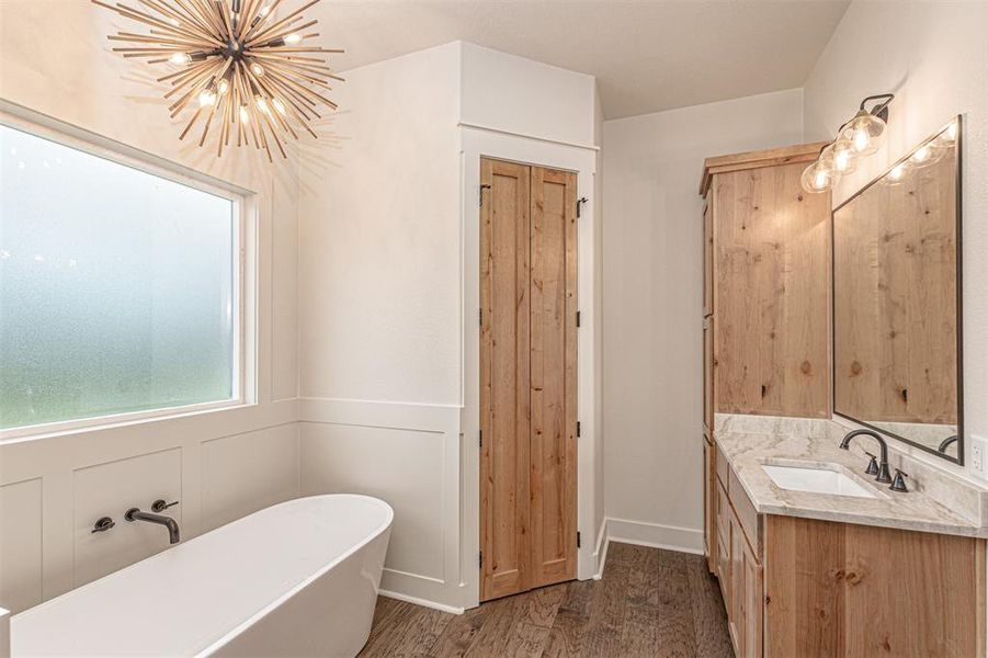 Full bathroom with vanity, a soaking tub, dark wood-type flooring, and suspended lighting