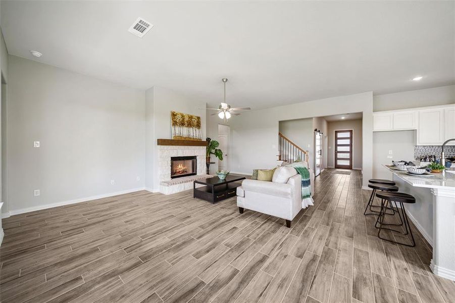 Living area featuring light wood-type flooring, a ceiling fan, recessed lighting, a stone fireplace, and stairway Living area featuring light wood-type flooring, a ceiling fan, recessed lighting, a stone fireplace, and stairway