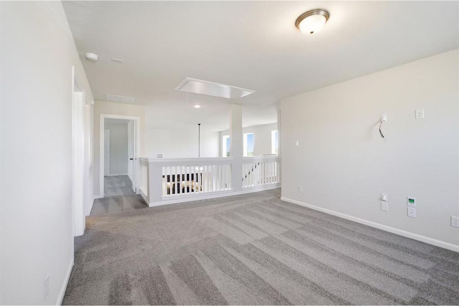 Carpeted loft area with white wall finishes, semi-flush mount lighting, and a white balustrade overlooking a lower level Carpeted loft area with white wall finishes, semi-flush mount lighting, and a white balustrade overlooking a lower level