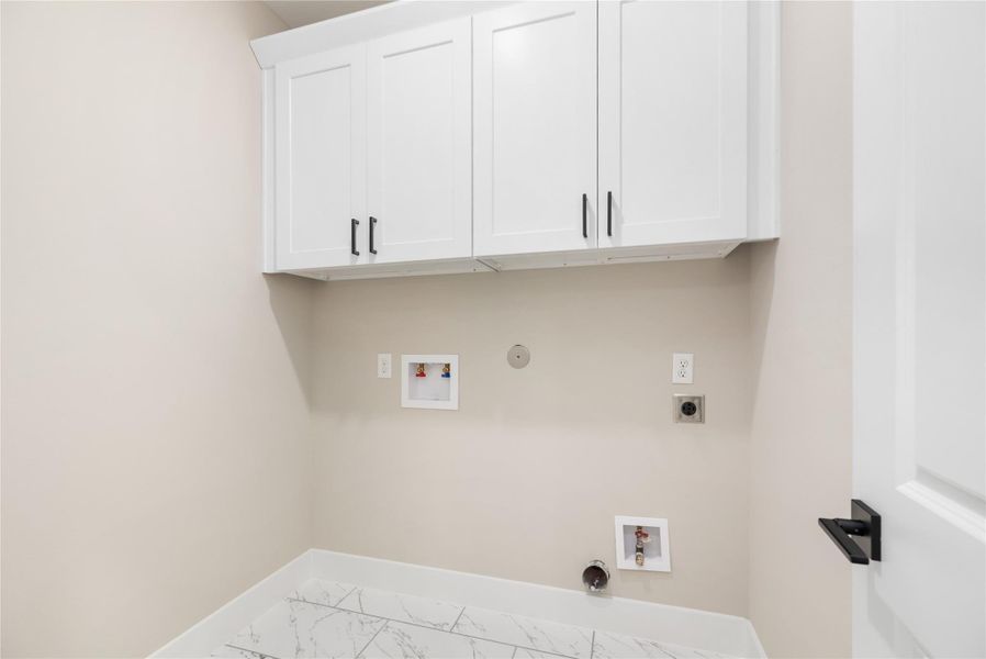 The dedicated laundry room comes equipped with sleek, white cabinetry providing abundant storage for your every day needs.