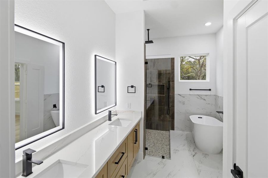 Full bathroom featuring a shower stall, a freestanding bath, double vanity, wainscoting, and tile walls