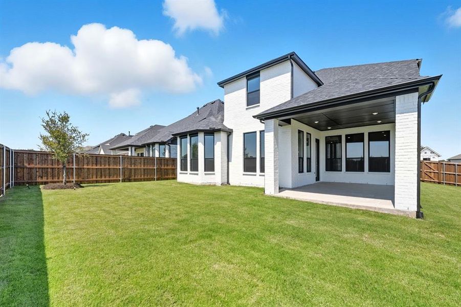 Back of property featuring a fenced backyard, a patio area, a shingled roof, and brick siding