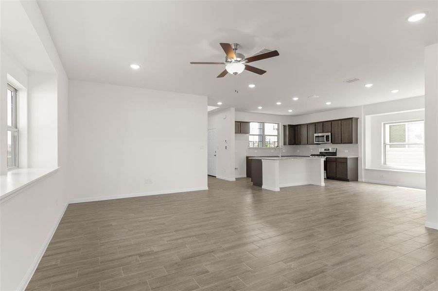 Unfurnished living room with a ceiling fan, baseboards, light wood finished floors, and recessed lighting