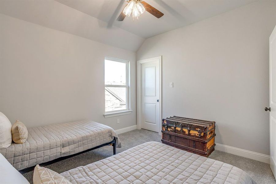 Carpeted bedroom with ceiling fan and vaulted ceiling