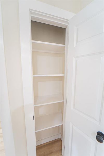 Linen storage/Built-in shelving unit featuring five white painted shelves and light wood-finish flooring