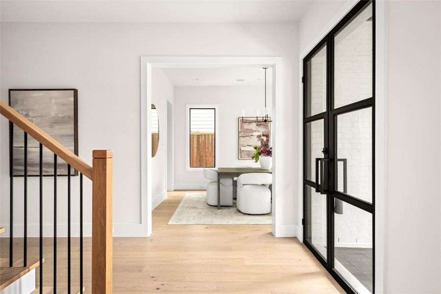 Bright entry with glass panel doors and natural oak floors offering a clear view into the dining area, highlighting the home's open and modern design. Bright entry with glass panel doors and natural oak floors offering a clear view into the dining area, highlighting the home's open and modern design.