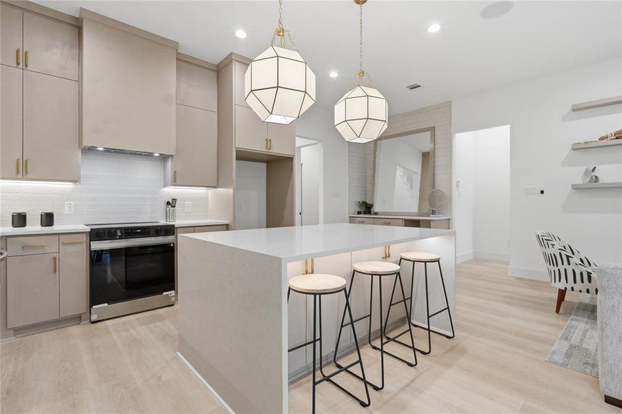 Modern kitchen featuring light wood-finish flooring and a central island with a solid surface countertop Modern kitchen featuring light wood-finish flooring and a central island with a solid surface countertop