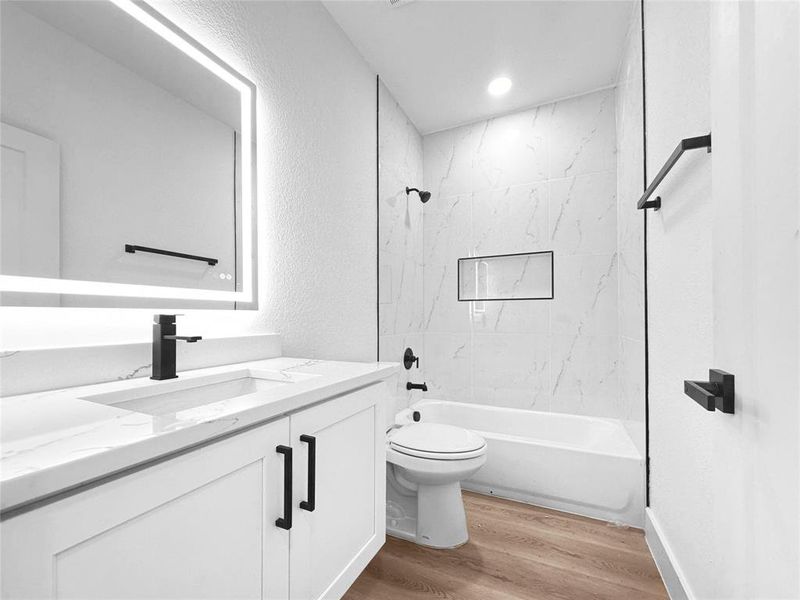 Full bath featuring a textured wall, vanity, shower / bathtub combination, and light wood-style flooring