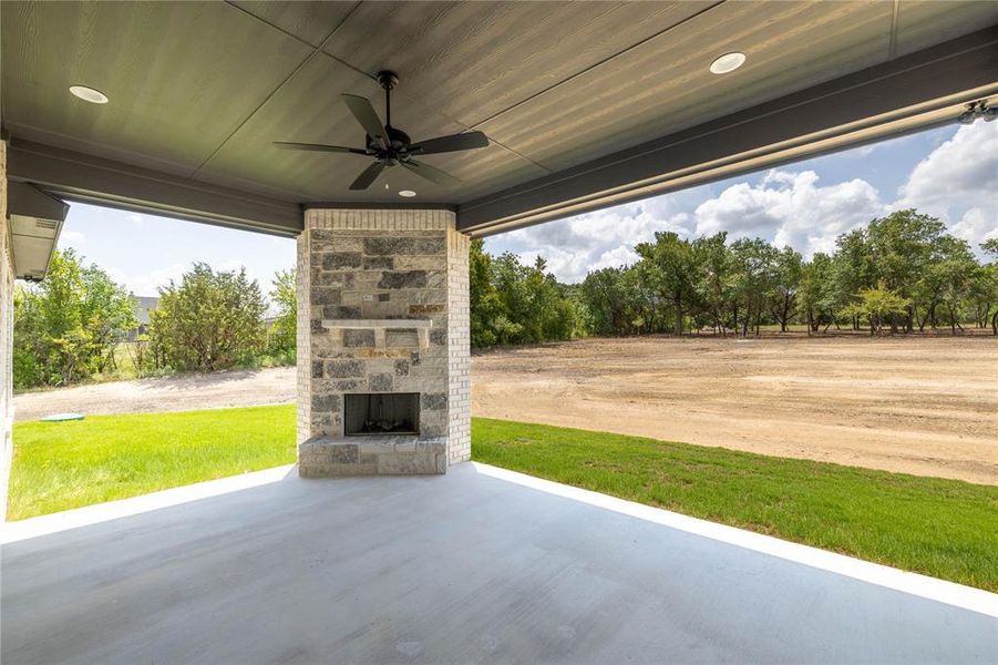 View of patio featuring an outdoor stone fireplace and ceiling fan