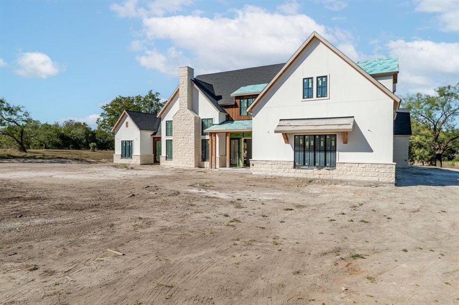 Rear view of property with stone siding, a chimney, and stucco siding Rear view of property with stone siding, a chimney, and stucco siding