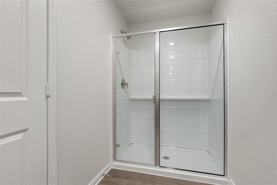 Full bath with a textured wall, dark wood-style floors, and a stall shower Full bath with a textured wall, dark wood-style floors, and a stall shower