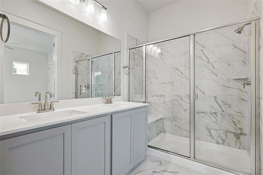 Bathroom featuring tile patterned flooring, double vanity, and a shower with shower door