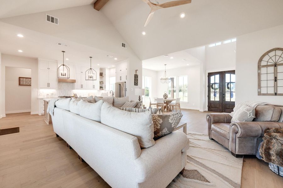 Living area featuring a chandelier, light wood-style floors, ceiling fan, and french doors