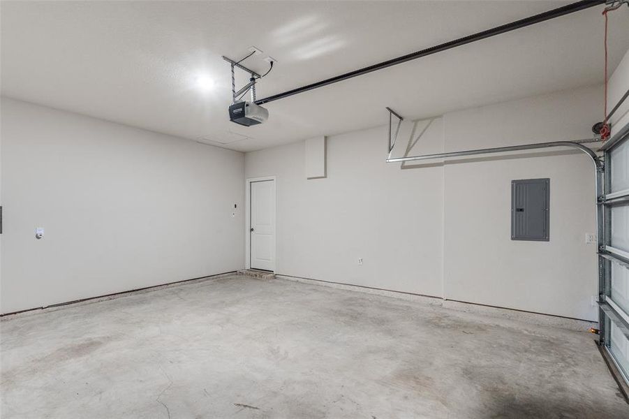 Garage featuring electric panel and a garage door opener Garage featuring electric panel and a garage door opener